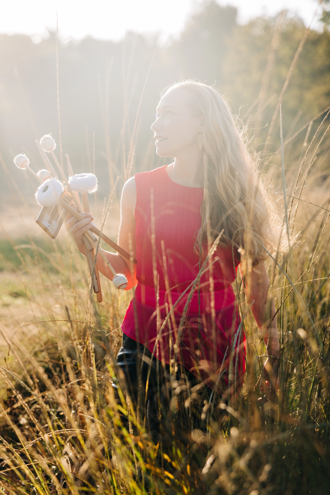 a photo of Bonnie Whiting walking through a meadow, with mallets in her hand