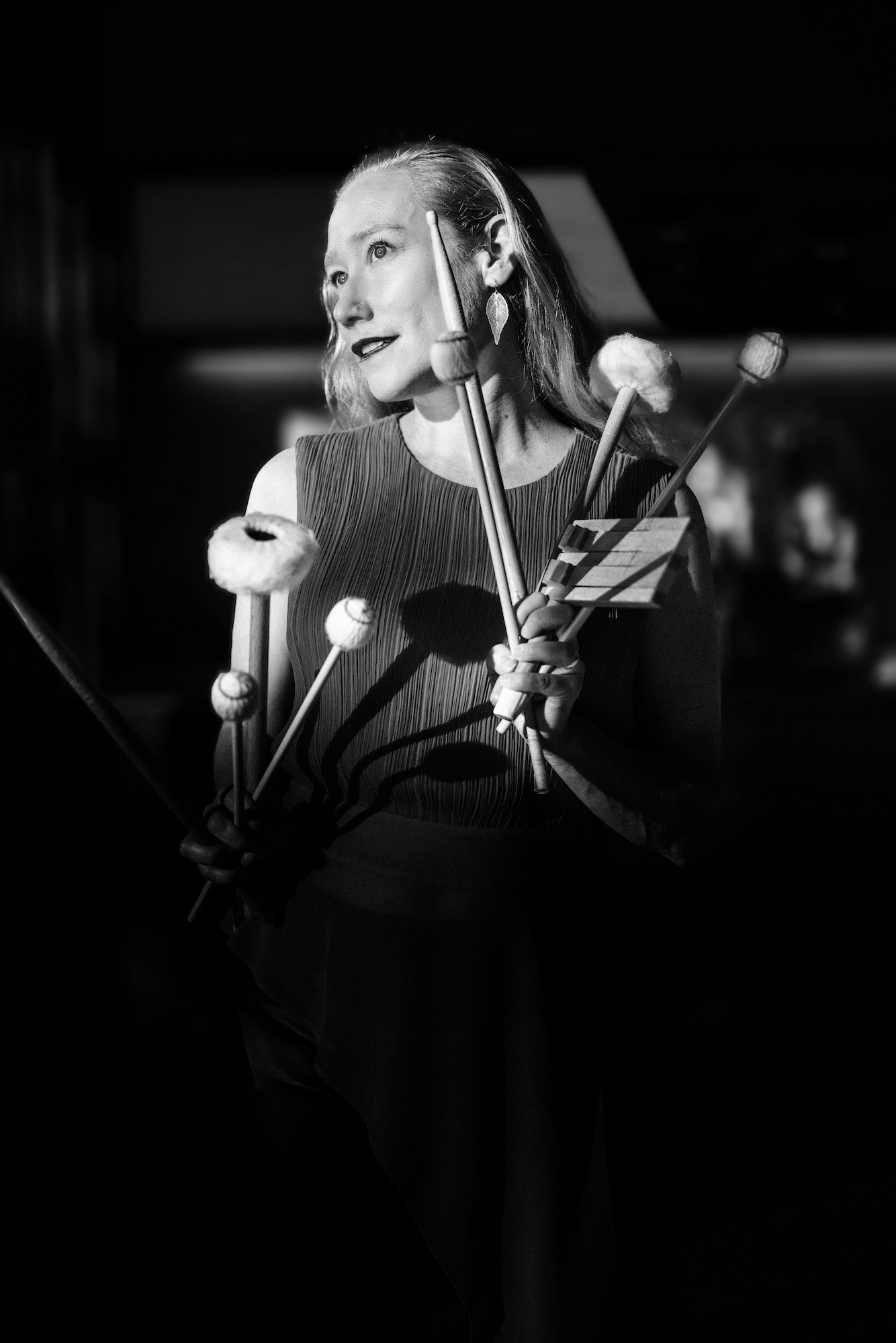 a black and white photo of Bonnie holding a bunch of sticks and mallets